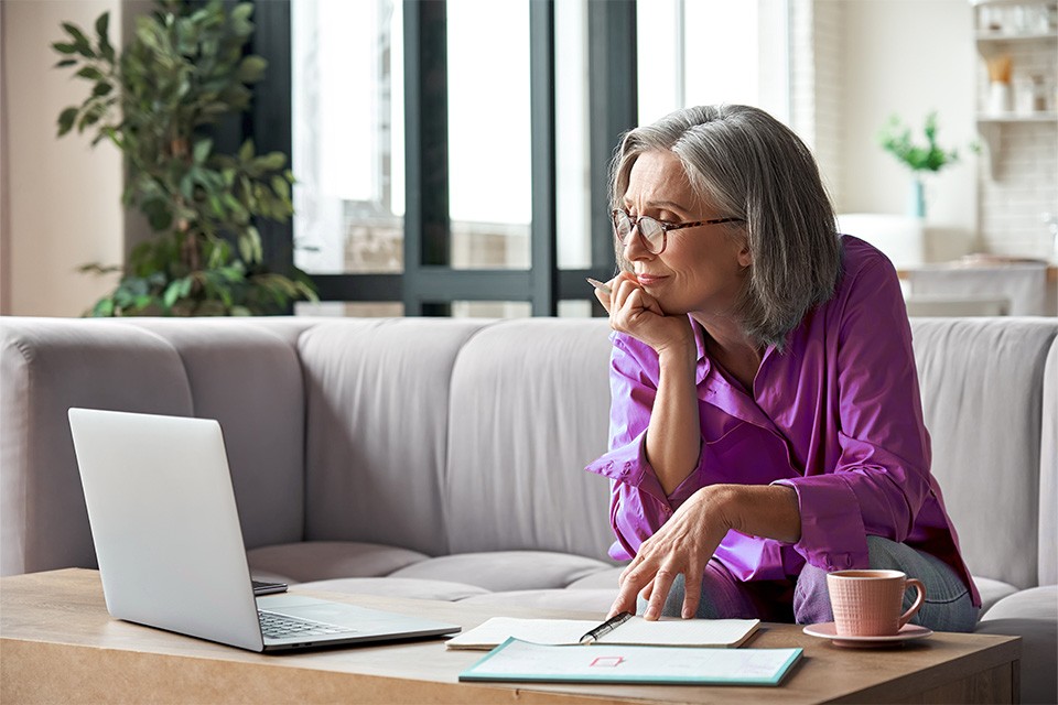 Lady sat on a sofa reading about how carbon emissions are calculated on a laptop