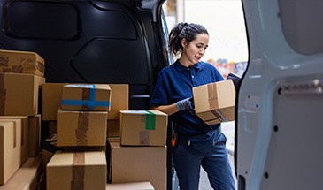 Young woman unloading a transit van while thinking about her carbon footprint.