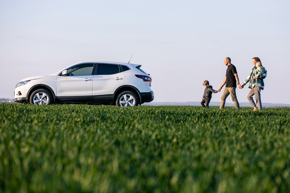 A family walking across grass to get to their car